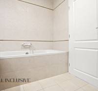 Fürdőszoba káddal, fehér ajtókkal és világos csempékkel egy kétszobás lakásban.