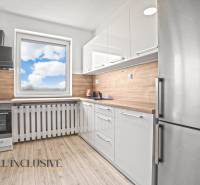 Fehér konyha egy kétszobás lakásban, fa dekor padlóval és kilátással az ablakból.