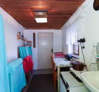 Konyhasarok a kertben függönyökkel, fából készült mennyezettel és egyszerű felszereléssel.