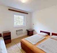 Hálószoba a házban három ággyal, éjjeliszekrény és ablak kilátással.