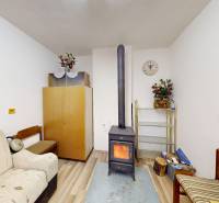 Szoba egy házikóban kályhával, kanapékkal és dekorációkkal, fa dekorációjú padlóval.