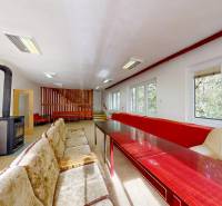 Szoba egy kunyhóban kályhával, kanapékkal, faasztalokkal és kilátással az erdőre.