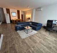 Nappali egy kétszobás lakásban kék kanapéval és íróasztallal.