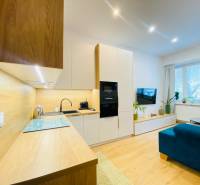 Konyhaszekrény fa dekorációval a kétszobás lakásban világos nappalival.