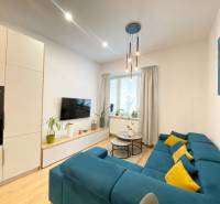 Nappali egy kétszobás lakásban kék kanapéval és fa mintázatú padlóval.