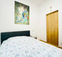 Hálószoba egy képpel a falon, ággyal és éjjeliszekrénnyel egy kétszobás lakásban.