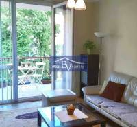 Nappali egy kétszobás lakásban tágas erkéllyel és kilátással a zöldre.