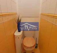 Bézs falakkal és csempékkel rendelkező WC egy kétszobás lakásban dekorációval.