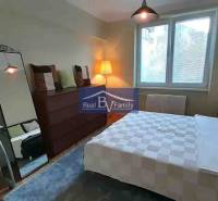 Hálószoba egy kétszobás lakásban nagy tükörrel és fa mintázatú padlóval.