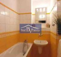 Fürdőszoba egy kétszobás lakásban meleg árnyalatú csempével és káddal.