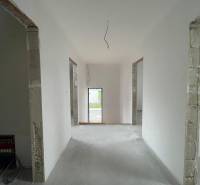 Családi ház belső tere fehér falakkal és nyitott ajtókkal a következő helyiségbe.