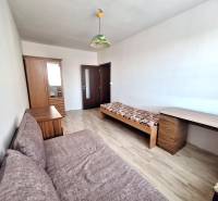 Szoba egy háromszobás lakásban, fa dekorációjú padlóval, ággyal és szekrénnyel.