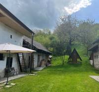 Az idősebb ház udvara pavilonnal a padon, kert természetes környezetben a dombon.