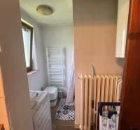 Kis fürdőszoba mosógéppel, radiátorral és WC-vel, alkalmas nyaralóhoz.