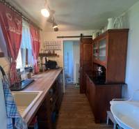 Konyha egy faházban rusztikus bútorokkal, mosogatóval és dekoratív függönyökkel.