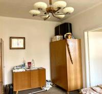 Szoba egy háromszobás lakásban fa bútorokkal és dekoratív csillárral.