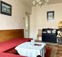 Nappali egy háromszobás lakásban kanapéval, szőnyeggel és dekoratív képekkel a falon.