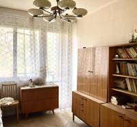 Szoba egy háromszobás lakásban könyvekkel, fa bútorokkal és fa dekoros padlóval.