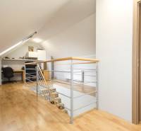 Tetőtéri dolgozószoba egy 4 szobás lakásban, fa dekorációjú padlóval és korláttal.