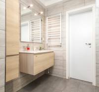 Fürdőszoba mosdóval, tükörrel és világos csempékkel egy 4 szobás lakásban.