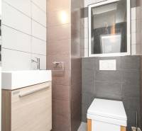 Fürdőszoba egy négy szobás lakásban világos csempékkel, mosdóval és WC-vel.