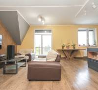 Négy szobás lakás nappalija fa dekoros padlóval, kényelmes ülőhelyekkel és világítással.