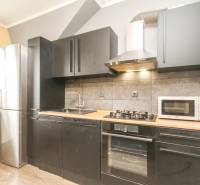 Konyha egy 4 szobás lakásban fekete szekrényekkel és fa dekor padlóval.