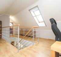 A 4 szobás lakás tetőtéri része íróasztallal és könyvespolccal, fa dekorációjú padlóval.