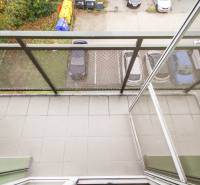 Erkély egy 4 szobás lakásban, kilátással a parkolóra és a zöldövezetre.