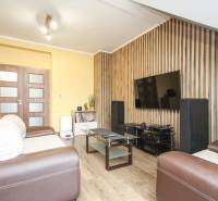 Nappali egy 4 szobás lakásban, TV-vel, kanapéval és fa mintázatú padlóval.