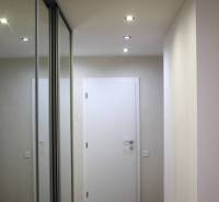 Folyosó beépített tükrös szekrénnyel és fa dekoros padlóval egy háromszobás lakásban.