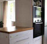 Konyha egy háromszobás lakásban, sötét szekrény beépített sütővel, mellette hűtőszekrény.