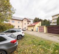 Irodák parkolója a Pozsonyi utcán, Zsolnán, autók és garázsok a háttérben.