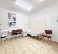 Szoba irodában csempével, mosdóval, székekkel és fekvőággyal.