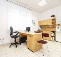 Iroda számítógéppel, asztallal és székkel, világos belső tér, polcok és mosdó.