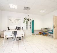 Irodát fehér bútorokkal, világtérképpel, zöld fallal, szaniter berendezéssel és növénnyel.