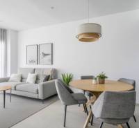 Világos nappali a nyaraló apartmanban szürke fotellel és faasztallal.