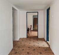 Egy családi ház folyosója csempével és bútorokkal a háttérben.