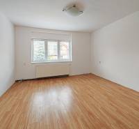 Egy családi ház szobája fa mintázatú padlóval és nagy ablakkal.