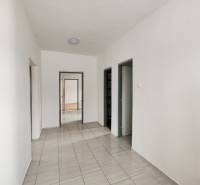 Családi ház folyosója csempével és fehér falakkal, amely az ajtóhoz vezet.