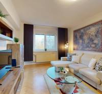 Nappali egy kétszobás lakásban kanapéval, TV-vel és fa dekorációjú padlóval.