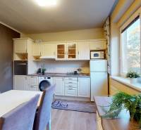 Konyha egy kétszobás lakásban étkezőasztallal, virágokkal és kilátással rendelkező ablakkal.