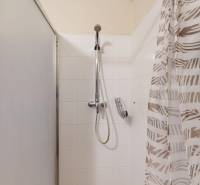 Fürdőszoba egy kétszobás lakásban fehér csempékkel és zuhanyzóval.