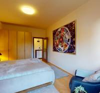 Hálószoba egy kétszobás lakásban nagy ággyal, falon lévő képpel és fa dekorációjú padlóval.