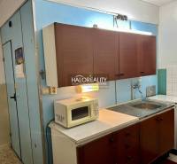Konyha régebbi szekrényekkel, mikrohullámú sütővel és tűzhellyel egy 4 szobás lakásban.