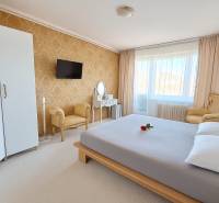 Hálószoba egy háromszobás lakásban elegáns bútorokkal, arany tapétával és fehér szőnyeggel.