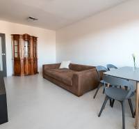 Nappali kanapéval és vitrinnel, fa hatású padlóval egy háromszobás lakásban.