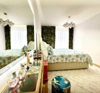 Hálószoba egy 3 szobás lakásban elegáns tükörrel és virágmintával.