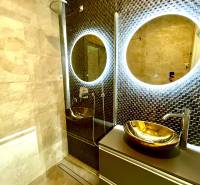 Luxusos fürdőszoba LED tükörrel és arany mosdótállal egy háromszobás lakásban.