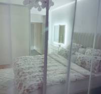 Hálószoba egy háromszobás lakásban ággyal, szekrénnyel és tükörrel.